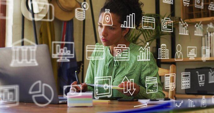 Analyzing Hispanic woman in green blouse reviewing financial data on laptop at home office with pen