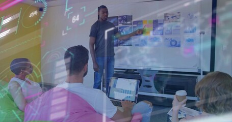 Presenting African American man pointing at whiteboard in conference room, with laptop, coffee cup