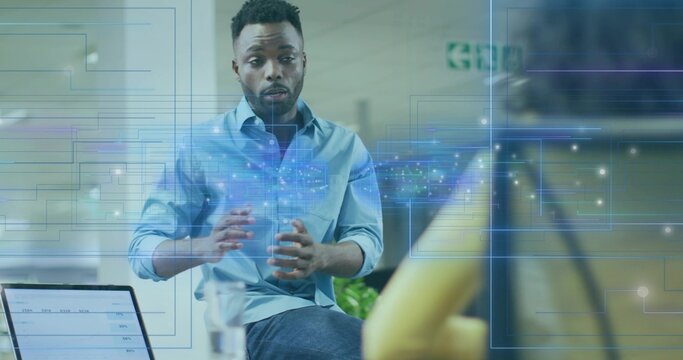 Gesturing African American businessman presenting network hologram in office with laptop and camera - Powered by Adobe