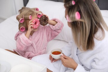 Mother and daughter having tea party on bed at home