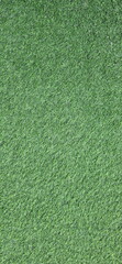 Vertical image of Artificial green grass background. Artificial turf made from synthetic fibers, two types of plastic,  (PE),  (PP). Surface of green synthetic fibers looks like natural grass.
