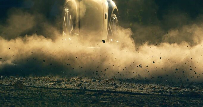Slow motion close up of car wheel accelerating on gravel terrain, lifting dust and debris at 1000 fps.. Perfect for concepts of adventure, energy, and motion.