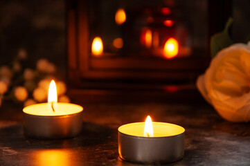 Tealight candles burning beside white flowers and a reflective lantern. Symbolic image for love, remembrance, spirituality, or cozy romantic atmosphere at home or during memorial moments.