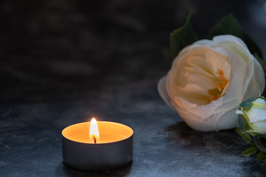 Single tealight candle burning in darkness, symbolizing remembrance and prayer during All Saints&rsquo; Day or All Souls&rsquo; Day. A peaceful image representing memory, spirituality, hope, and eternal light.