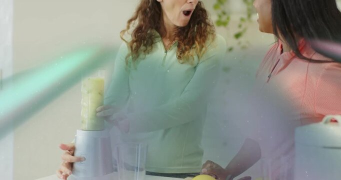 Home cook securing jar and pressing power button, blending greens, fruit, friend admiring smoothie