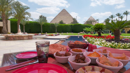 Delicious Egyptian meal served outdoors with a beautiful view of the pyramids, palm trees, and...