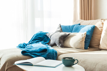 Festive Living Room with Cushions, Blue Blanket, Mug, and Open Book