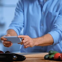 Man photographing food on a kitchen counter with a smartphone