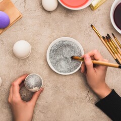 Hands decorating easter eggs with glitter and paintbrushes