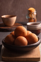 Traditional Colombian buñuelo-fritter with coffee – rustic Latin American breakfast in warm low key lighting