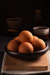 Traditional Colombian buñuelo-fritter with coffee – rustic Latin American breakfast in warm low key lighting