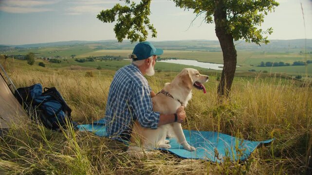 Digital Detox, Nature Healing. Senior Man Sits With His Dog by a Tent, Admiring the Mountain View. A Quiet Moment of Disconnection, Mental Recharging, and Deep Presence in Nature