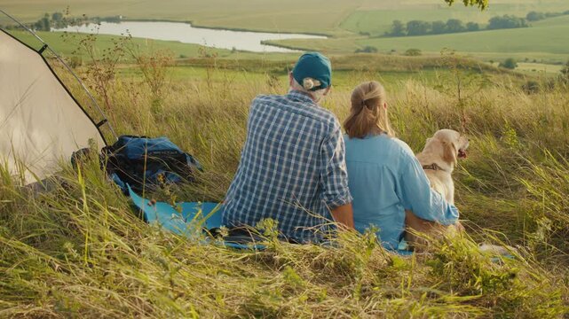 Pet-Inclusive Family Time. Senior Man Sits With His Family and Dog by a Tent, Admiring the Beautiful Landscape. A Peaceful Moment of Togetherness, Nature, and Joyful Living With a Beloved Pet