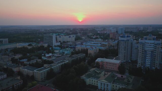 Aerial evening view of Orel city in Russia with river, Strelka, main buildings, churches and roads. Beautiful cityscape with lights reflecting on water at sunset, showing urban architecture, skyline.