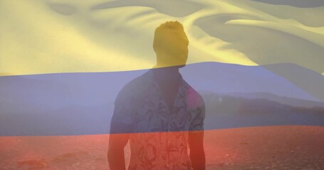 sunset glow causing transparent Colombian flag overlay rippling around man on shore for marketing - Powered by Adobe
