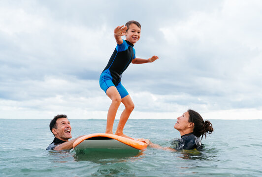 Happy multiracial family having surfing lesson at the beach during summer vacation  - Powered by Adobe