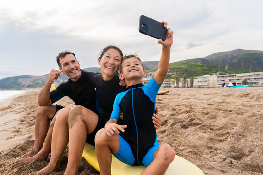 Happy multiracial family having surfing lesson at the beach during summer vacation  - Powered by Adobe