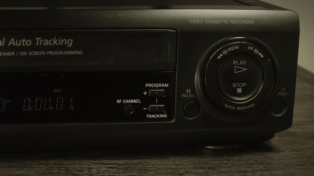 Vintage vcr inserting and playing vhs cassette. Close up, intro shot. Old vcr deck with a vhs tape loading, recalling past video technology. A retro video and entertainment concept.