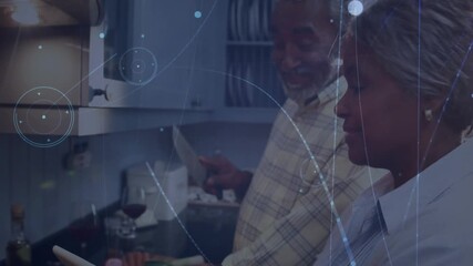 Senior couple scrolling tablet and cooking with tech animated overlay while chopping vegetables - Powered by Adobe