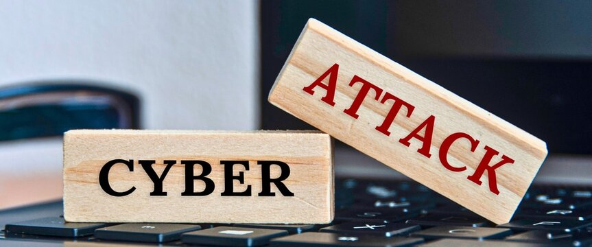 Wooden blocks spell out cyber attack on a keyboard