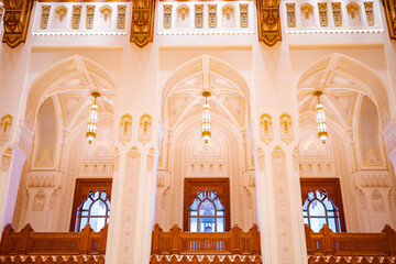 A magnificent view of the interior arches and chandeliers of the Royal Opera House in Muscat, Oman. The scene captures the grandeur of Islamic architecture with its geometric patterns, gold details