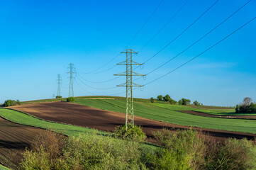 Overhead power line with conductors suspended by towers, rural area of Ponidzie, Poland