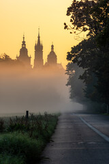 Foggy sunrise on Blonia meadow in Krakow, Poland, with St Mary's church and Town Hall towers in the background,