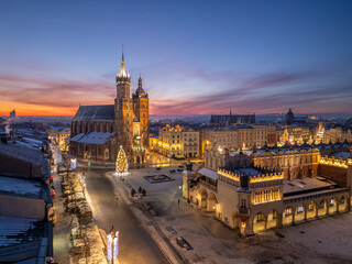 Aerial late night / dawn view of snow covered Main Square with St Mary's church and Cloth Hall with Christmas Tree in Krakow, Poland