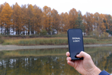 Hand holding smartphone displaying signal lost in nature