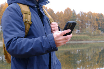 Hiker man using phone near autumn lake