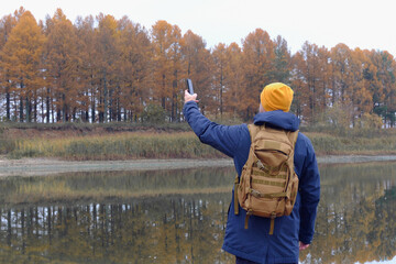 A man picks up a connection on his phone with poor network coverage by autumn river
