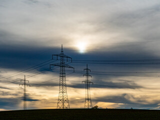 Hochspannungsmasten unter einem bizarren Wolkenhimmel
