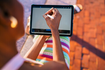 African woman actively drawing abstract shape on tablet, showcasing digital precision, seamless stylus control, and hands-on interaction with modern design tools.