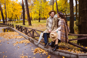 Charming couple enjoying a cozy moment outdoors in a city park during autumn. They share a joyful smile, conveying warmth and connection on a sunny day.