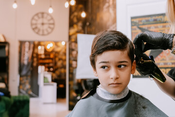 With classic decor in the background, the boy gazes sideways during his haircut, giving a glimpse of curiosity.