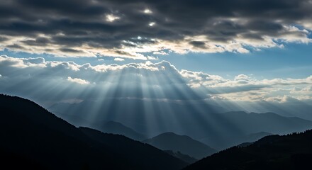 Sunlight rays breaking through clouds over mountain range