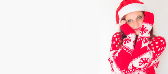 Young woman in a red Santa hat and sweater smiling while posing against a white background