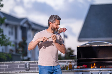 Handsome man preparing barbecue grill outdoor. Man cooking tasty food on barbecue grill at backyard. Chef preparing food on barbecue. Millennial man grilling meat on grill. Bbq party. Meal grilling.