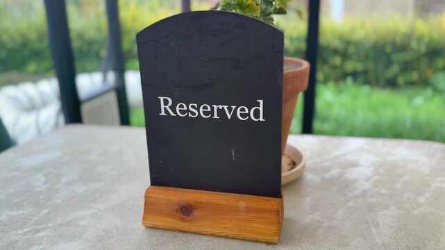 black and white reserved sign on top of restaurant dining table with garden view