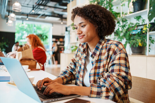 A Young Woman Engaged in Work on Her Laptop While Seated in a Contemporary Cafe Environment