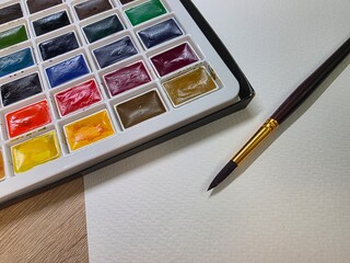 Watercolor paint set with brush and paper. Close-up of watercolor palette, brush, and textured paper ready for painting—perfect for art, creativity, and DIY projects