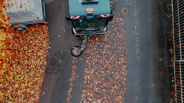 Drone view of street sweeper cleaning road covered with autumn leaves in Finland