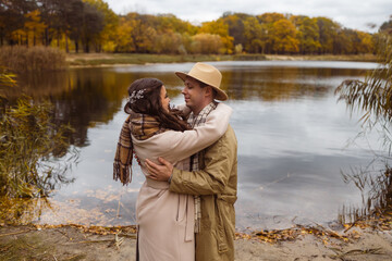 Charming couple enjoying a cozy moment outdoors in a city park during autumn. They share a joyful smile, conveying warmth and connection on a sunny day.