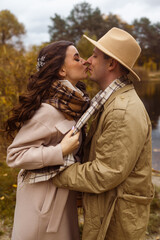 Charming couple enjoying a cozy moment outdoors in a city park during autumn. They share a joyful smile, conveying warmth and connection on a sunny day.