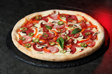 Tasty pizza with melted cheese and assorted toppings on a dark background. Perfect for menu, delivery or food promo.