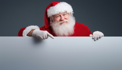 Joyful Santa Claus Smiling and Pointing at a Blank Signboard