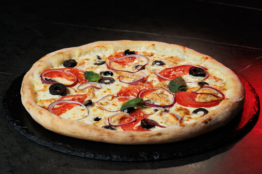 Tasty pizza with melted cheese and assorted toppings on a dark background. Perfect for menu, delivery or food promo.