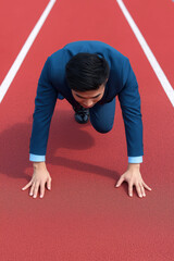 Businessman in Suit Preparing to Race on Running Track Surface