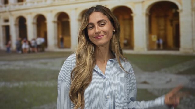 Woman showing two finger peace sign and sticking tongue out in roman courtyard with archways and cobblestone plaza; playfulness joy spontaneity fun.
