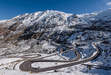 panoramic view of the Transfagarasan Highway winding through the snowy peaks of the Carpathian...